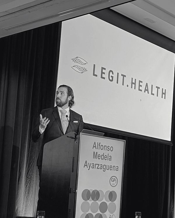 Alfonso Medela en un atril presentando Legit.Health, con el logotipo en la pantalla de detrás